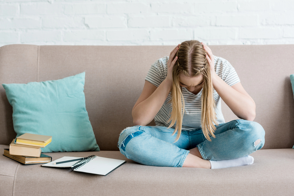Tini l�ny �l a kanap�n, k�nyvekkel, �s fej�t fogja depresszi�san
